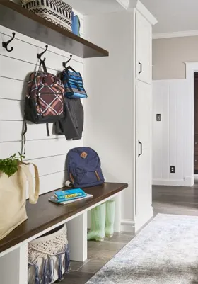 Organized mud room with bench, coat rack, backpacks, ideal for outdoor gear and mud prevention.